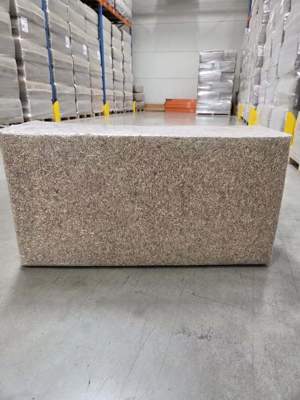 20 kg LinoBed flax bedding bale standing in front of pallet racks